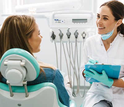 Dentist smiling while taking notes on clipboard
