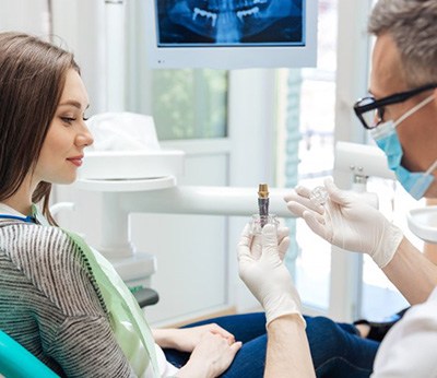 Dentist showing patient a dental implant model during a consultation