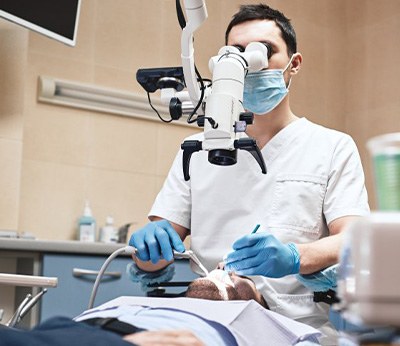 Patient laying back in chair as oral surgeon examines their mouth