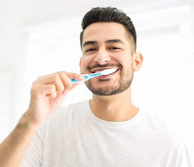 Man smiling while brushing his teeth
