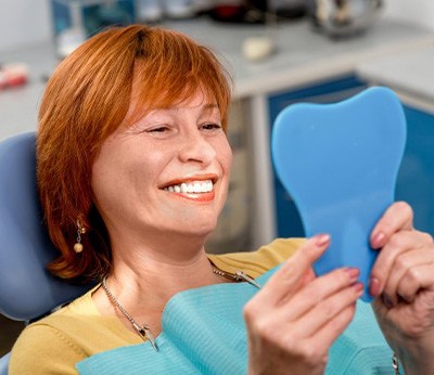 Patient smiling in small dental mirror
