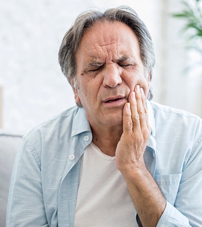 Man sitting on couch with pain in jaw