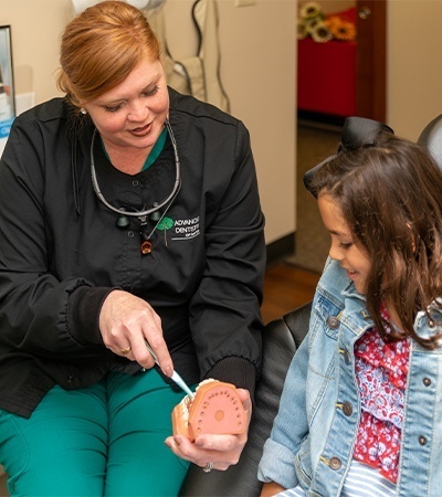 Dental team member showing child good oral hygiene skills after dental sealant treatment