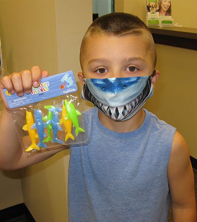 Child smiling with toy gift from dentist after pulp therapy