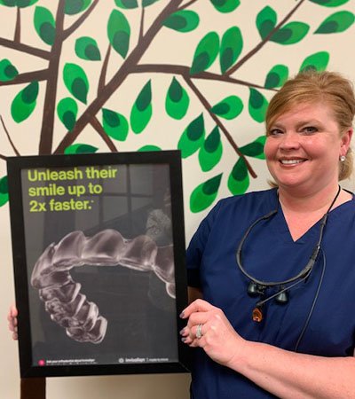 Dental team member holding an Invislaign poster