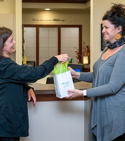 Patient taking her at home teeth whitening kit from a dental team member