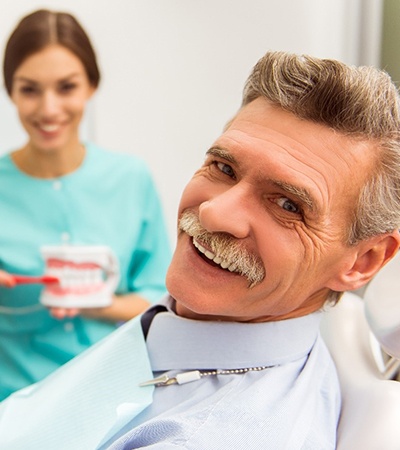 Dentist showing smiling man how to brush dentures