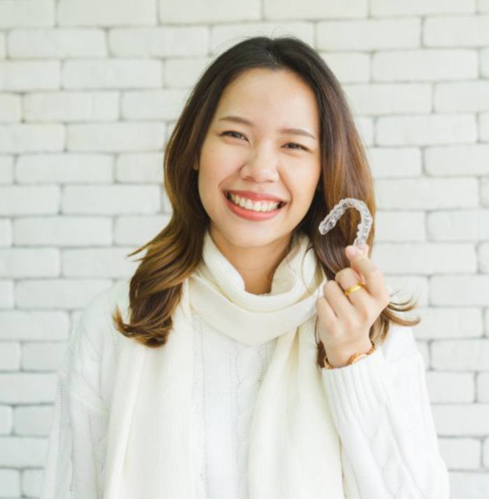 woman holding clear aligner for Invisalign in Sugarcreek Township