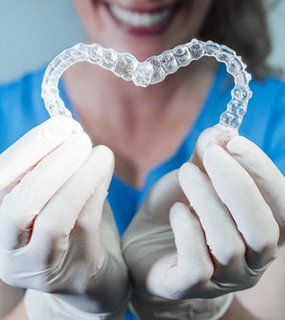 dental hygienist holding two clear aligners in the shape of a heart