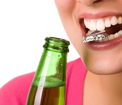 Closeup of woman holding bottle cap in teeth