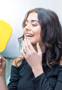 Patient smiling while looking in dental mirror