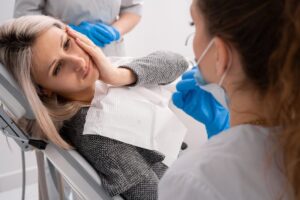 Woman holding face in pain in the dentist's chair. 